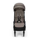 Nuna TRVL 360 lightweight travel stroller in Cedar brown, shown in a front view against a clean white background. The stroller features an extended sun canopy, a brown leatherette-accented pushbar and rotating armbar, a harness with a magnetic buckle, 360-degree swivel wheels, and an under-seat storage basket.