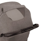 Nuna TRVL 360 lightweight travel stroller in Cedar brown, shown from the rear with the canopy extended to reveal a mesh ventilation window and a brown leatherette pushbar against a clean white background.