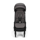 Nuna TRVL 360 lightweight travel stroller in Pewter grey, shown in a front view against a clean white background. The stroller features an extended sun canopy, a brown leatherette-accented pushbar and rotating armbar, a harness with a magnetic buckle, 360-degree swivel wheels, and an under-seat storage basket.