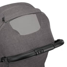 Nuna TRVL 360 lightweight travel stroller in Pewter grey, shown from the rear with the canopy extended to reveal a mesh ventilation window and a brown leatherette pushbar against a clean white background.