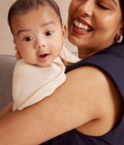 Woman holding a baby wearing a white bib, both smiling.