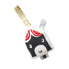 A plush baby toy shaped like a stylized face with a black and white body, red swirl details on the top, a white and gray ear, and a striped cream-and-yellow strap, shown on a plain white background.