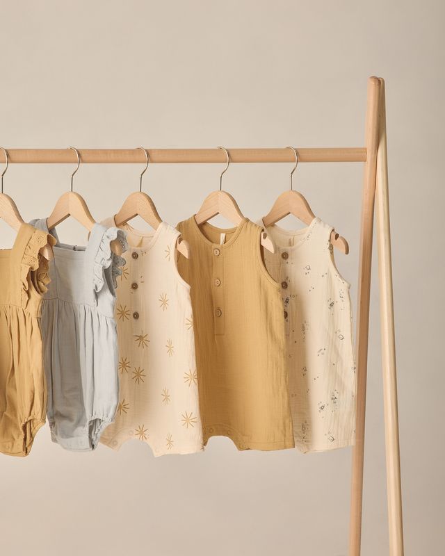 Children's clothing on hangers against a beige wall