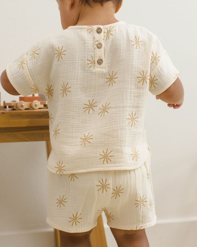 Child wearing a cream-colored outfit with gold star patterns indoors.