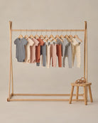 Wooden clothing rack with baby clothes on a beige background