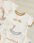 Children's clothing with cartoon designs and text on a neutral background