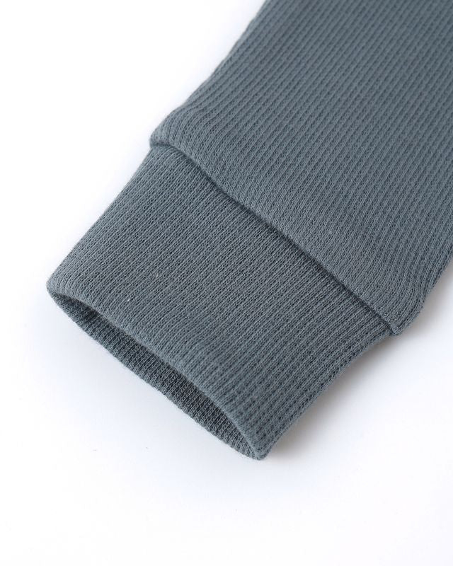 Close-up of a ribbed gray sweater sleeve on a white background