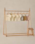 Wooden clothing rack with baby clothes on a beige background