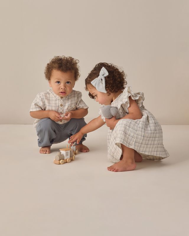 Two children playing with wooden toys on a plain background