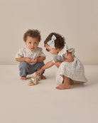 Two children playing with wooden toys on a plain background
