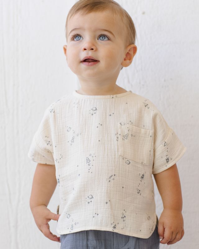 Baby wearing a light-colored shirt with subtle patterns against a white background