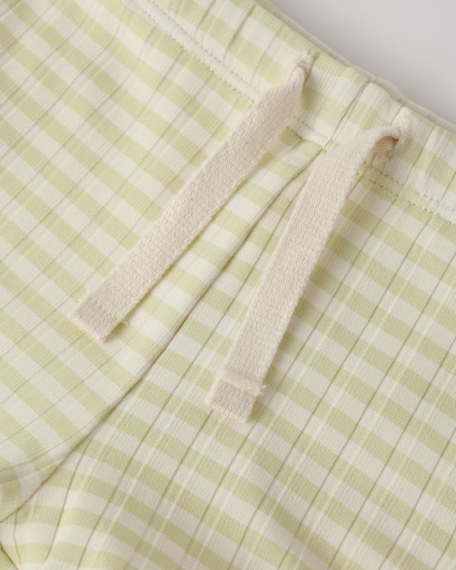 Green and white checkered fabric with a folded edge on a light gray background