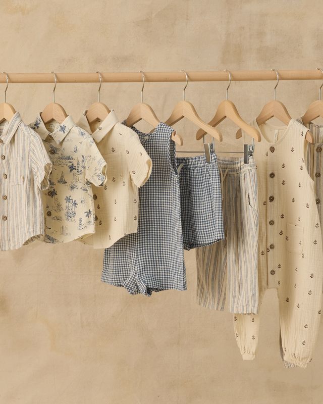 Children's clothing on hangers against a beige wall