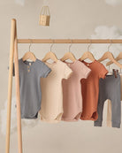 Wooden clothing rack with baby clothes on a neutral background