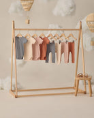 Wooden clothing rack with baby clothes on a neutral background