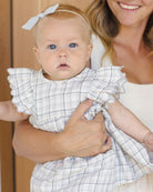 Baby in a checkered outfit held by a smiling woman