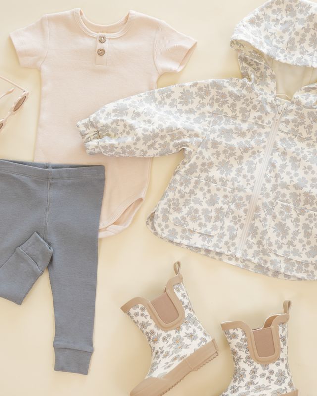 Baby clothing including a shirt, pants, and shoes on a neutral background