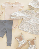 Baby clothing including a shirt, pants, and shoes on a neutral background