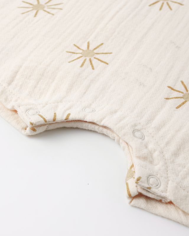Beige baby romper with gold star patterns on a white background