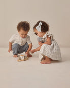 Two children playing with toys on a plain background