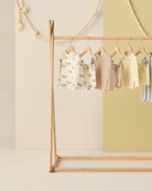 Children's clothing on a wooden rack against a light background