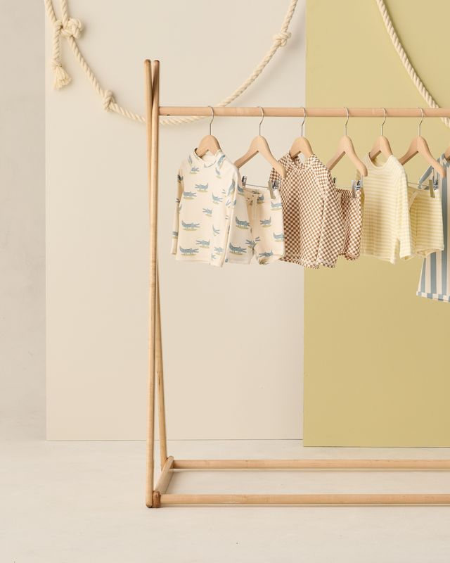 Children's clothing on a wooden rack against a light background