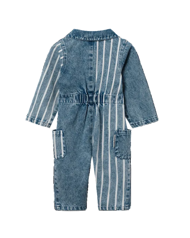 A baby romper in blue denim with vertical white stripes, featuring a button-up back, elastic waist, and front patch pockets, shown against a plain white background.