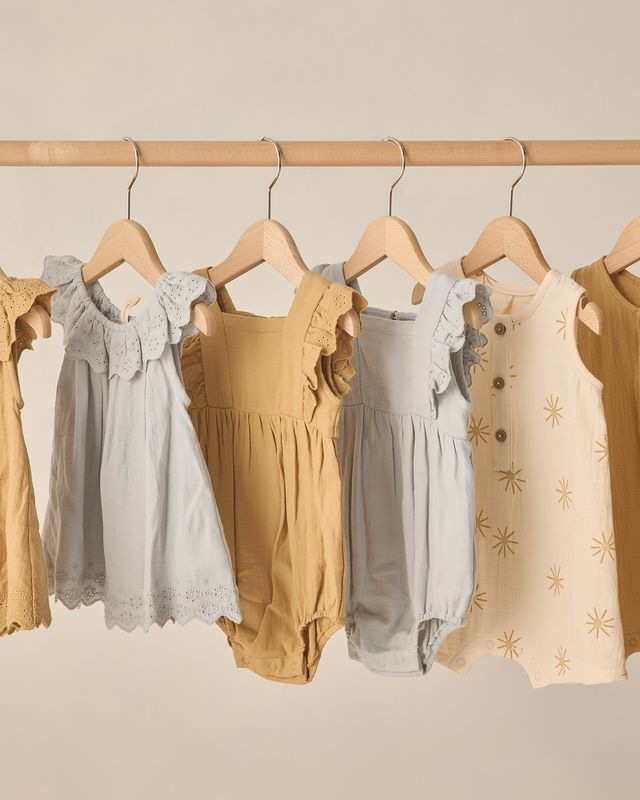 Children's clothing on hangers against a neutral background
