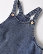 Close-up of a blue denim overall with button details on a white background
