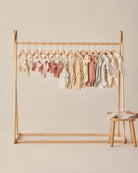 Wooden clothing rack with baby clothes on a beige background