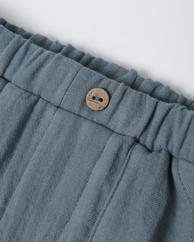 Close-up of blue fabric with a button on a white background
