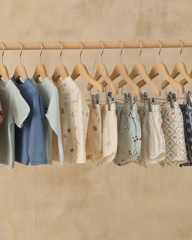 Children's clothing on hangers against a beige wall