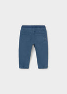 Blue denim pants shown from the back, featuring a wide elastic waistband, two back patch pockets, and elastic cuffs at the ankles, photographed on a light gray background.
