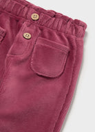 Close-up of dusty rose corduroy pants showing the elastic waistband, two decorative wooden buttons, and a front patch pocket.