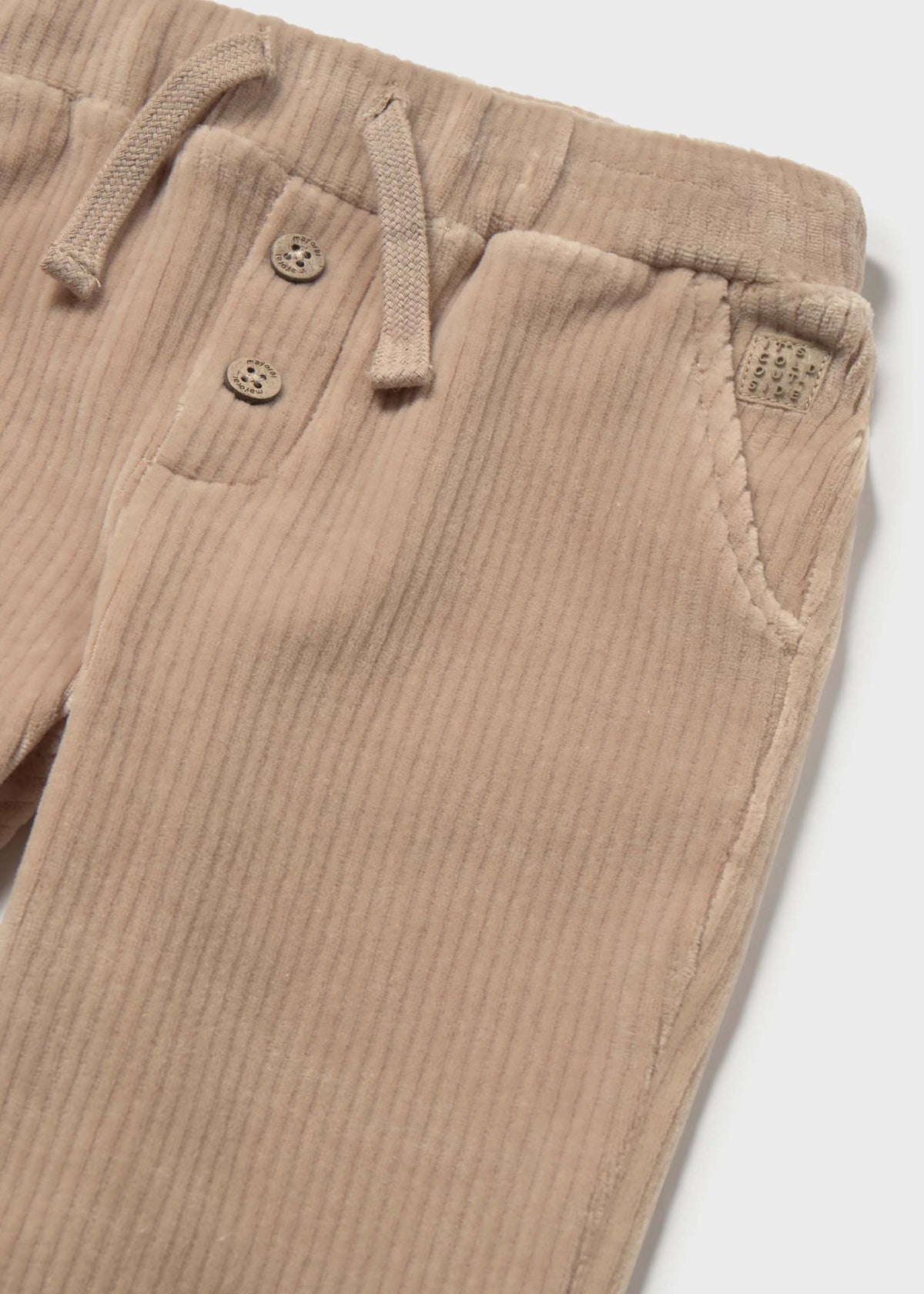 Close-up of beige ribbed pants with button details on a white background