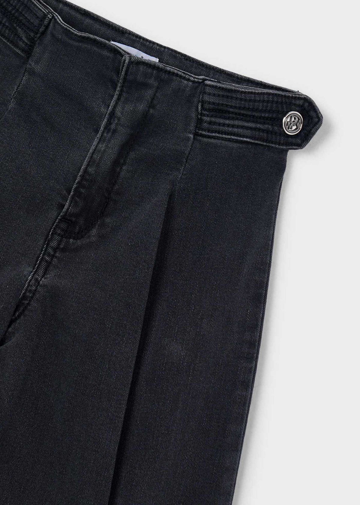 Close-up of black pants with a button on a light gray background