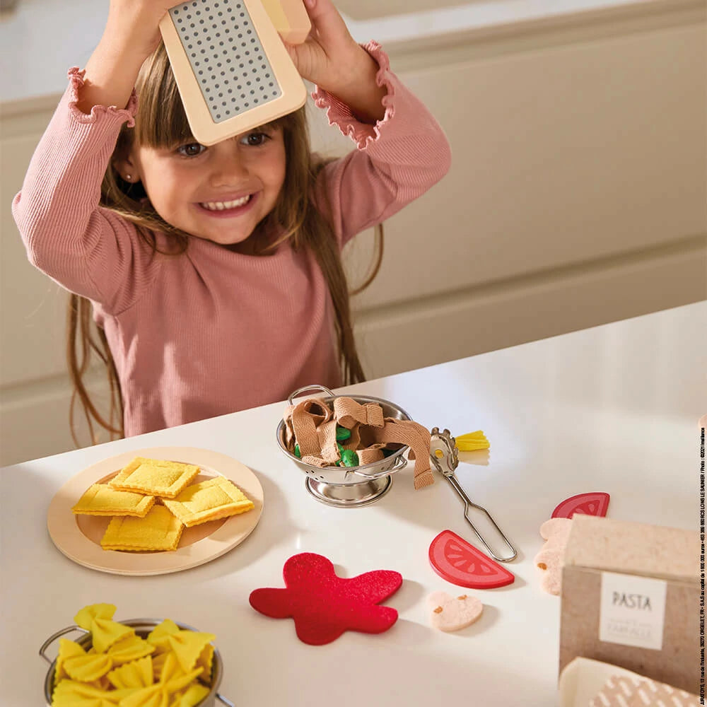 Child playing with a pasta-making kit on a table
