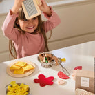 Child playing with a pasta-making kit on a table