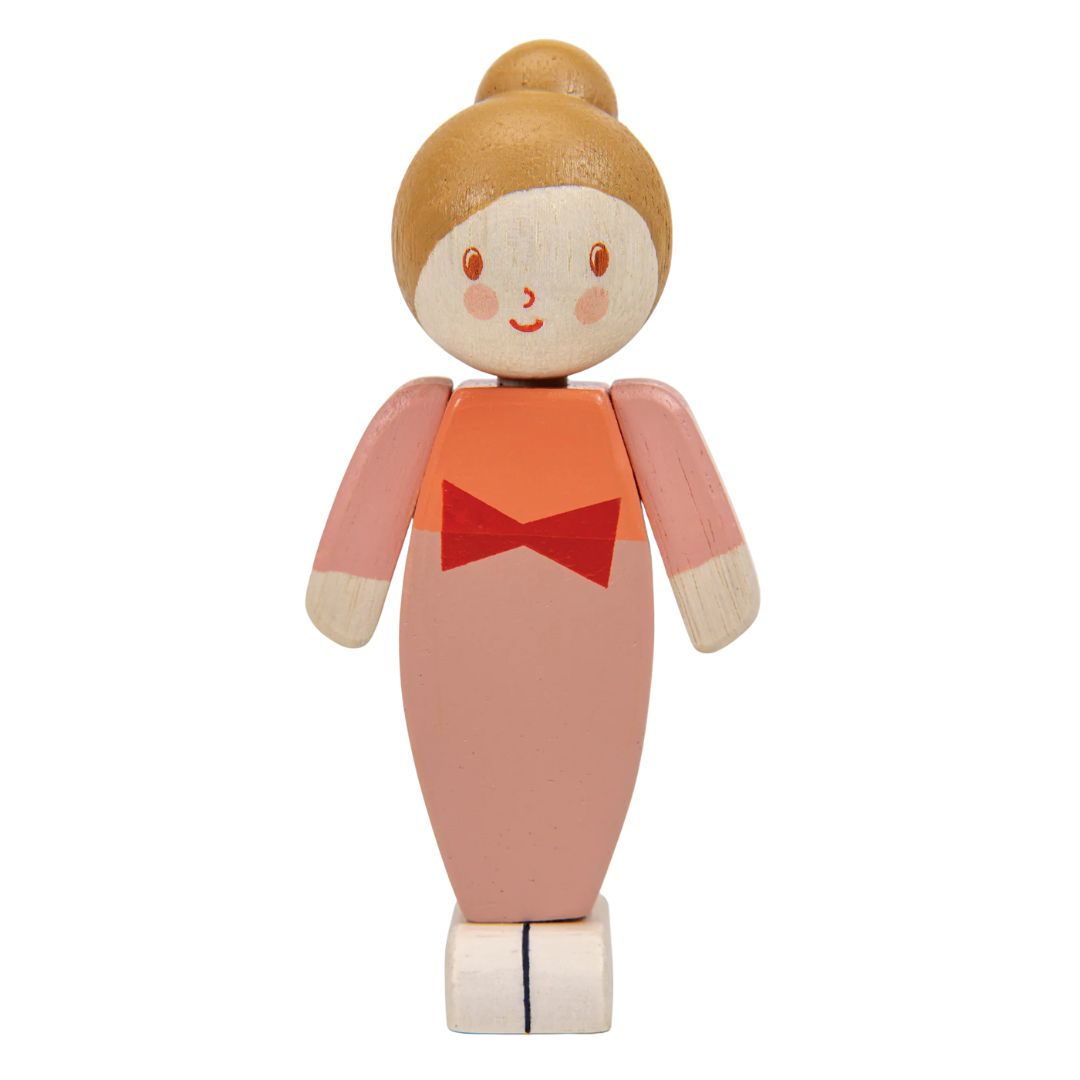 A wooden toy doll with a round painted head, peach-colored body, orange top, and red bow detail, shown on a plain white background.