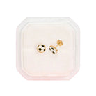 Pair of gold and black checkered earrings in a pink jewelry box on a white background