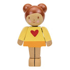 Wooden toy figure of a girl with a yellow sweater and red heart on a white background
