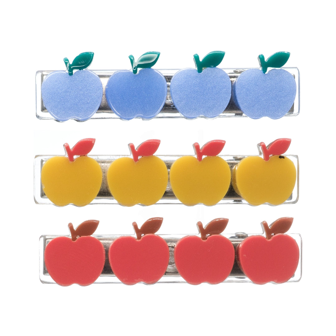 Six clear plastic hair clips shaped like apples, arranged in three rows of two. The top row clips feature light blue apples with green leaves, the middle row clips feature yellow apples with red leaves, and the bottom row clips feature red apples with brown leaves.