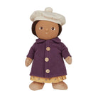 A cloth doll with brown fabric skin and dark brown hair, wearing a cream-colored beret, a textured purple coat with wooden buttons, and a yellow patterned skirt, isolated on a white background.