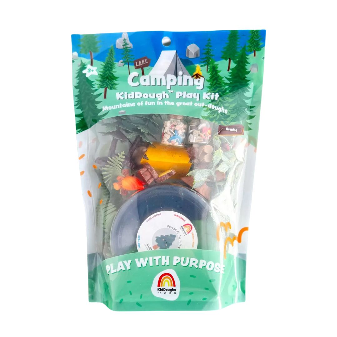 A packaged KidDough KidDough Camping Play Kit in a resealable stand-up pouch with a colorful camp scene printed on the front, showing assorted toy pieces and a dark round component inside.