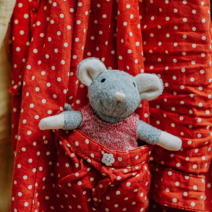 Stuffed mouse toy in red polka dot outfit against a red polka dot background