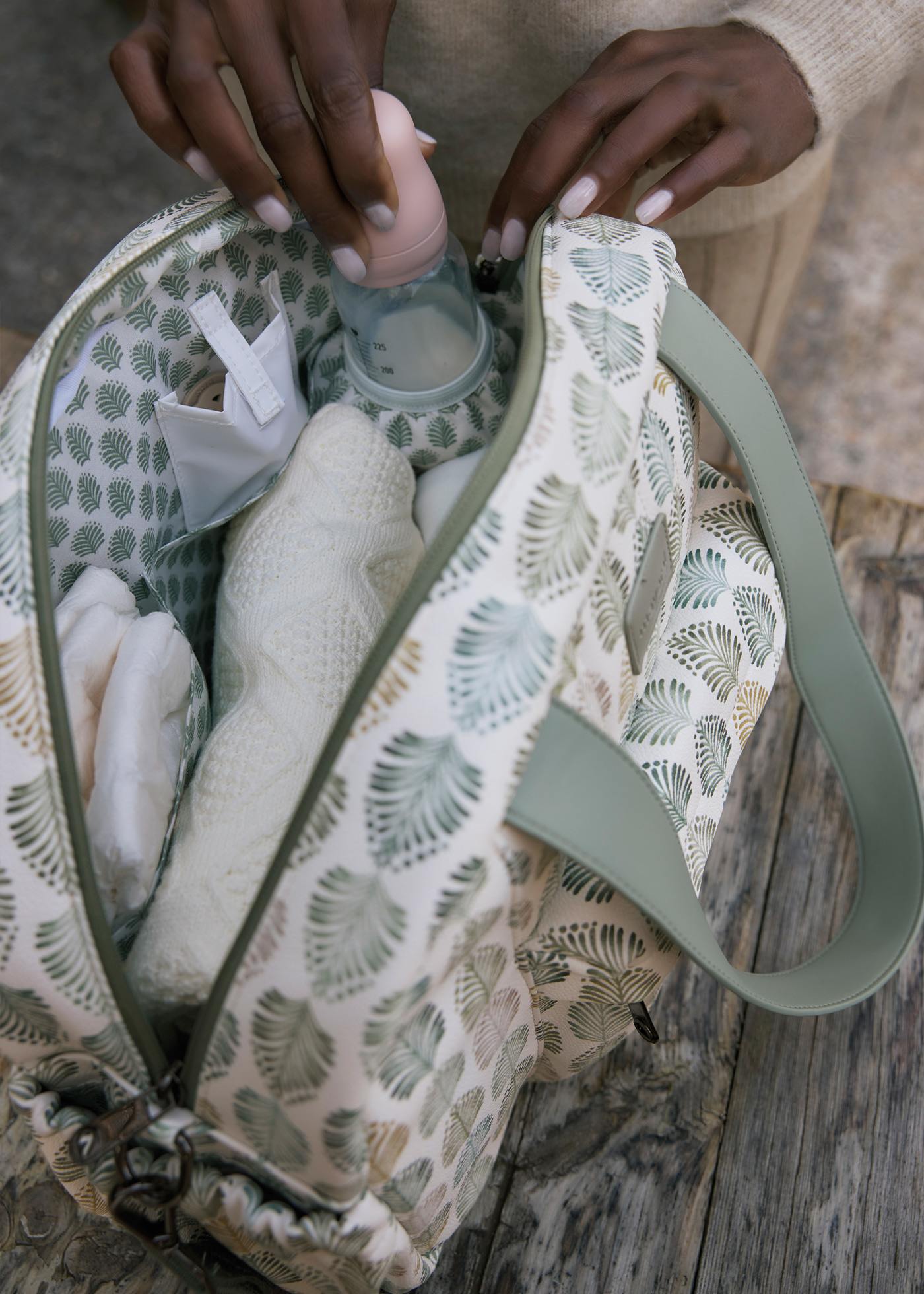 Person holding a patterned bag with items inside on a wooden surface
