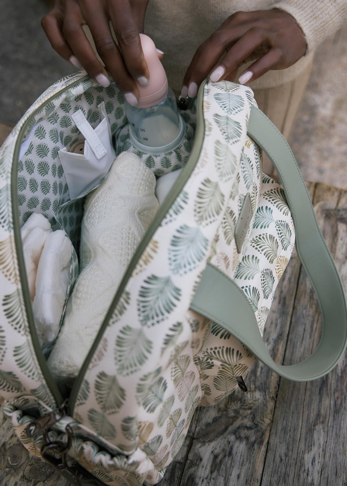 Person holding a patterned bag with items inside on a wooden surface