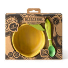 Oli&Carol wooden dinnerware set in its original packaging, featuring a yellow bowl, a green spoon, and a green leaf-shaped utensil on a brown kraft cardboard box.