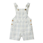 A pair of children's overall shorts with adjustable shoulder straps, featuring a white and light blue plaid pattern, wooden buttons, and front pockets, shown against a plain white background.