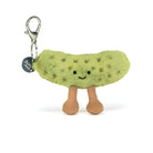 A plush pickle keychain from Jelly Belly, featuring a light green fuzzy body with a smiling face, brown corduroy legs, and a silver lobster clasp with a black brand tag.